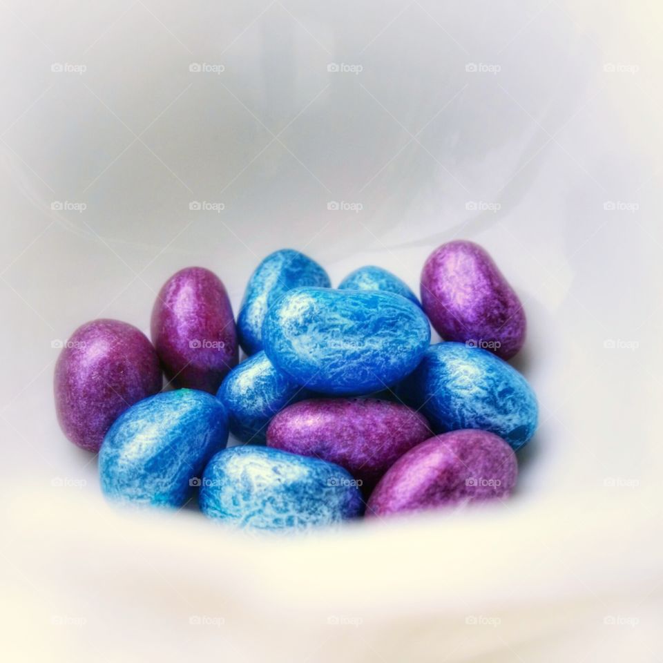 Electric blue and purple jellybeans in a white bowl