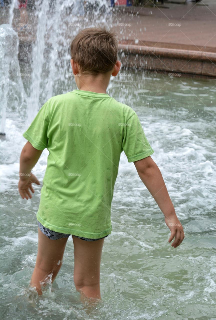 child in water fountain city summer time