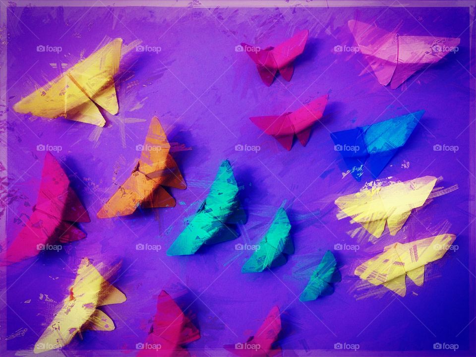 Colorful paper butterflies on violet wall