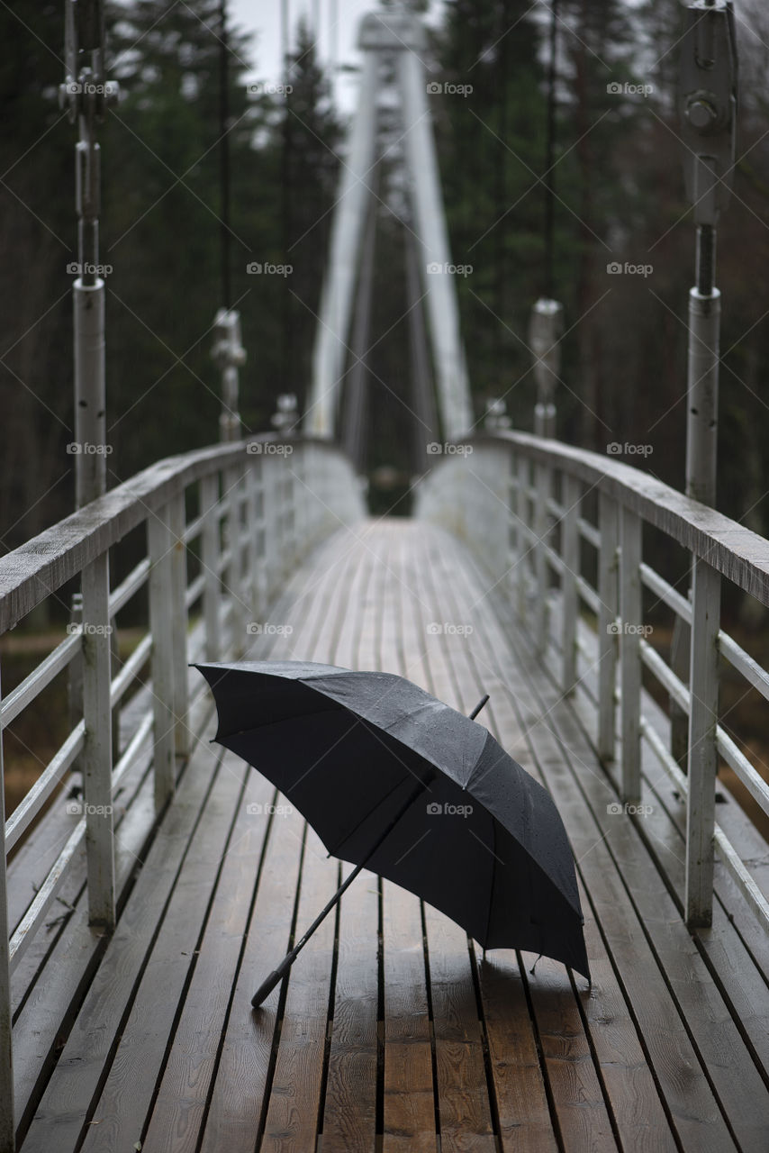 Black umbrella on wooden bridge