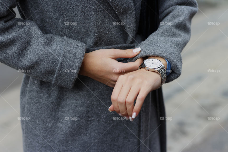 Girl in gray coat checks time, looks at clock, hurry, business