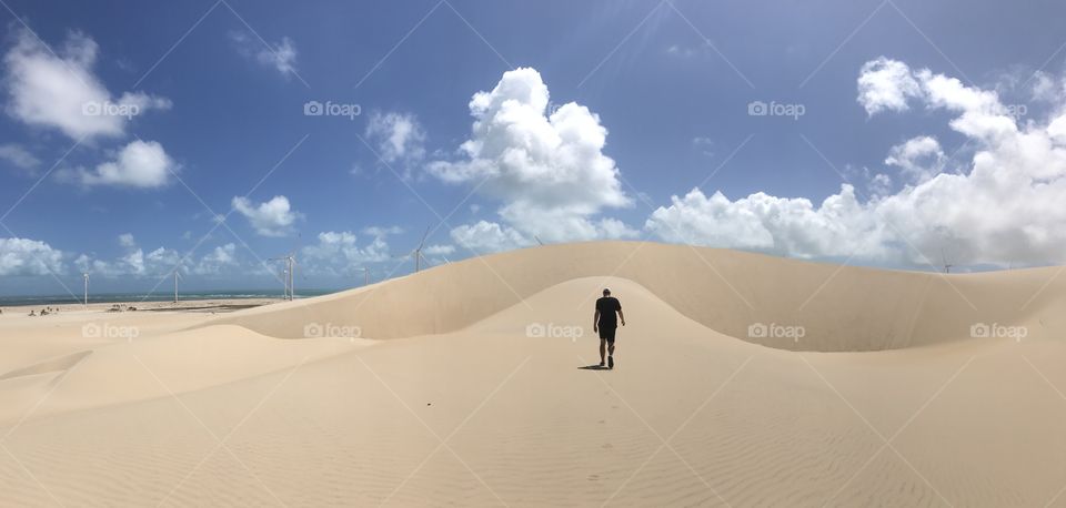 Man walking over sand dunes
