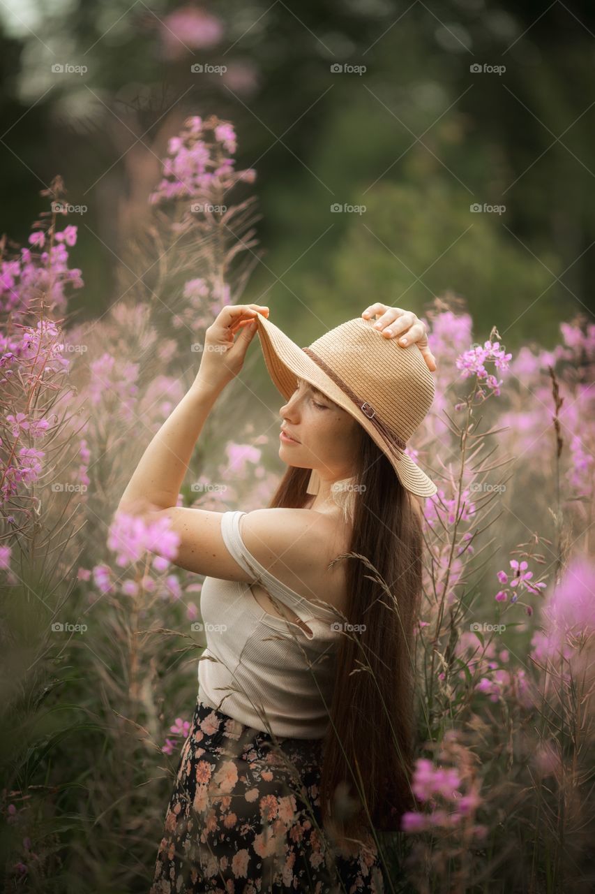 Beautiful young woman in a field of blossom flowers in boho style