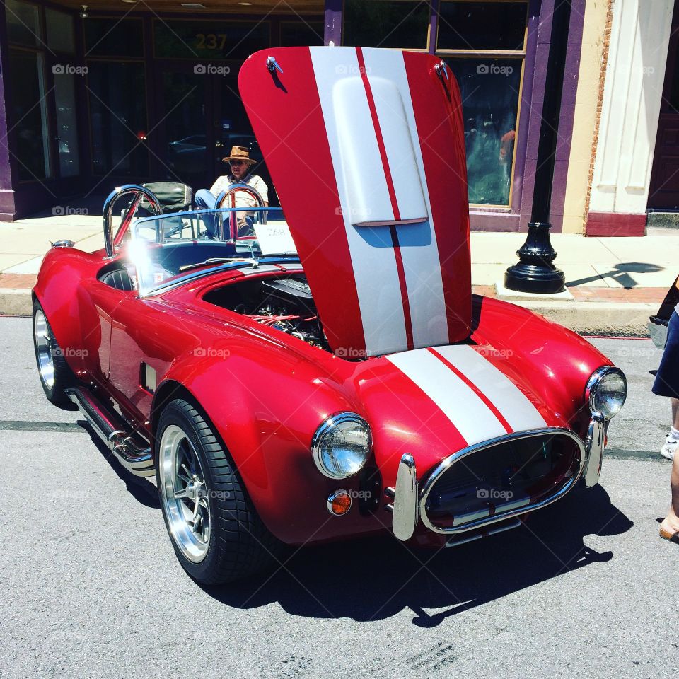 Red Shelby cobra with white stripes at car show on street