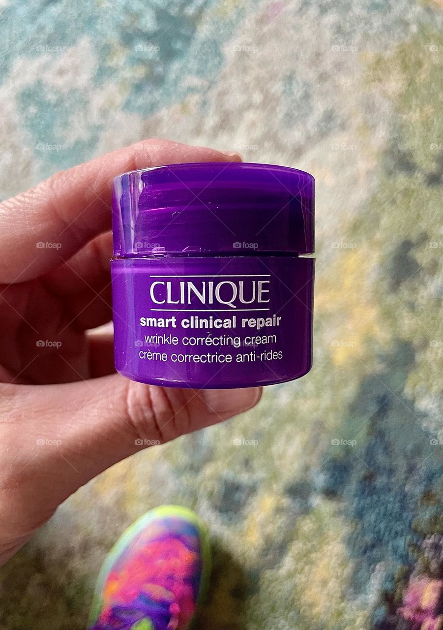 Woman’s hand holding Clinique Facial Cream for wrinkles, woman trying different facial products, trying to make your skin look younger, finding the fountain of youth 