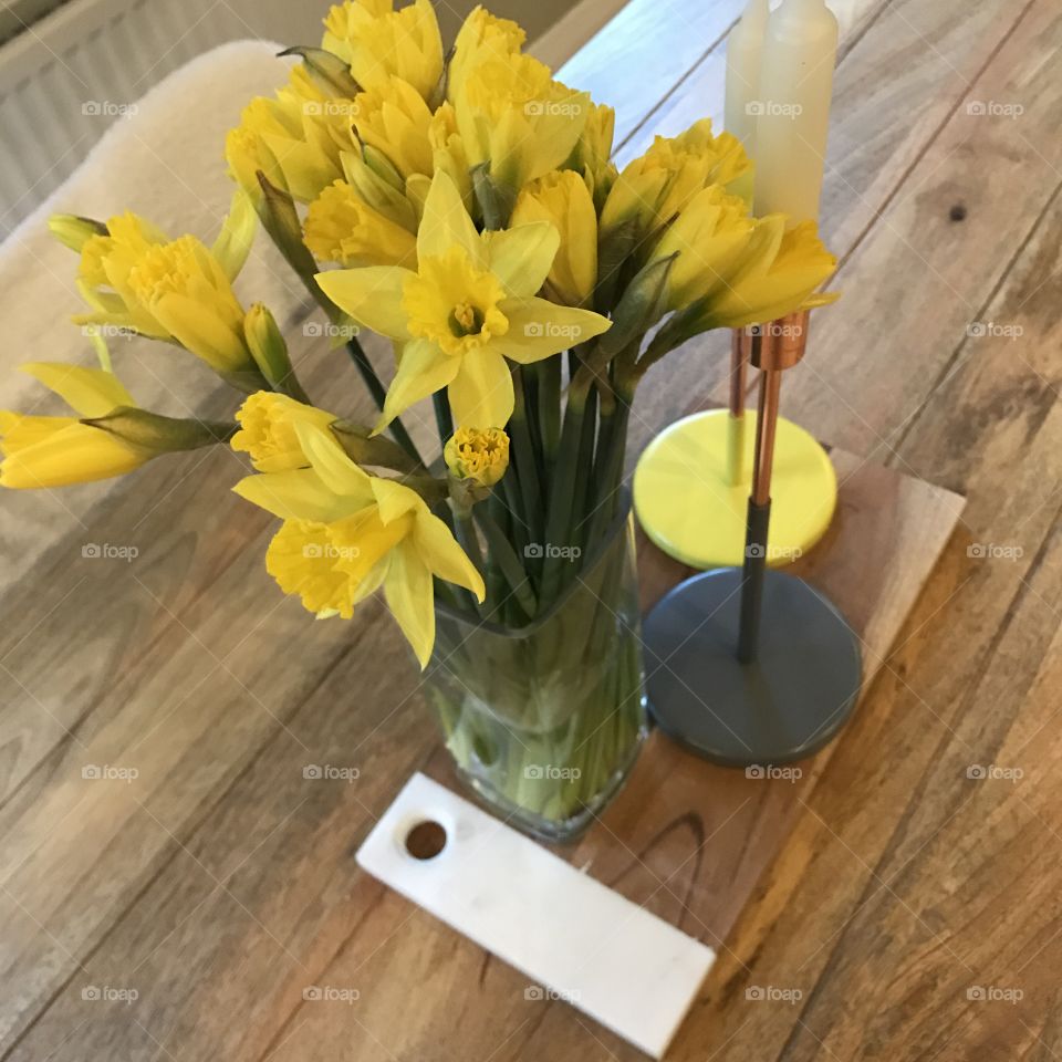 Yellow daffodils in case on wooden table. 