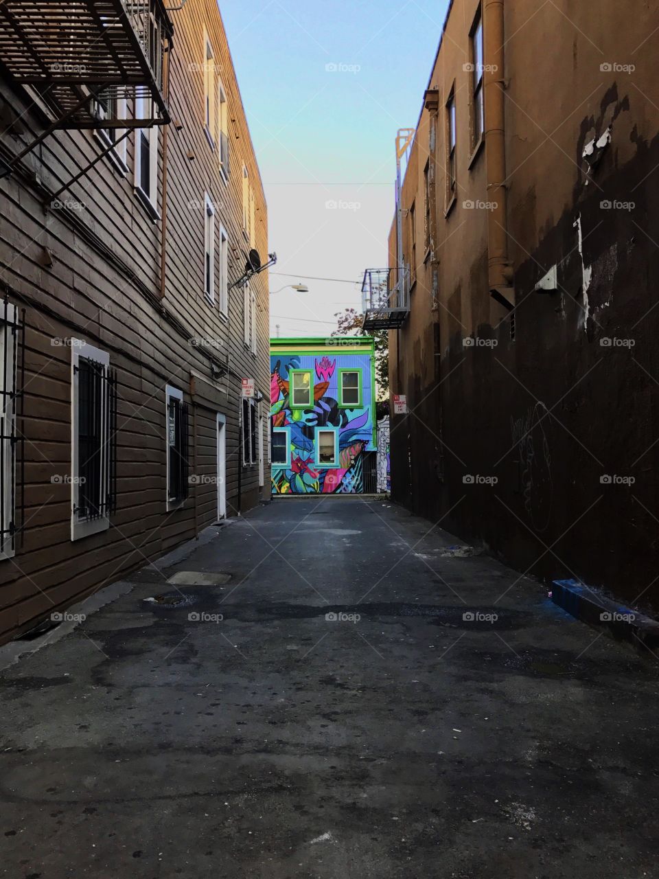 A San Francisco gray alley with a rainbow of building graffiti at the end.