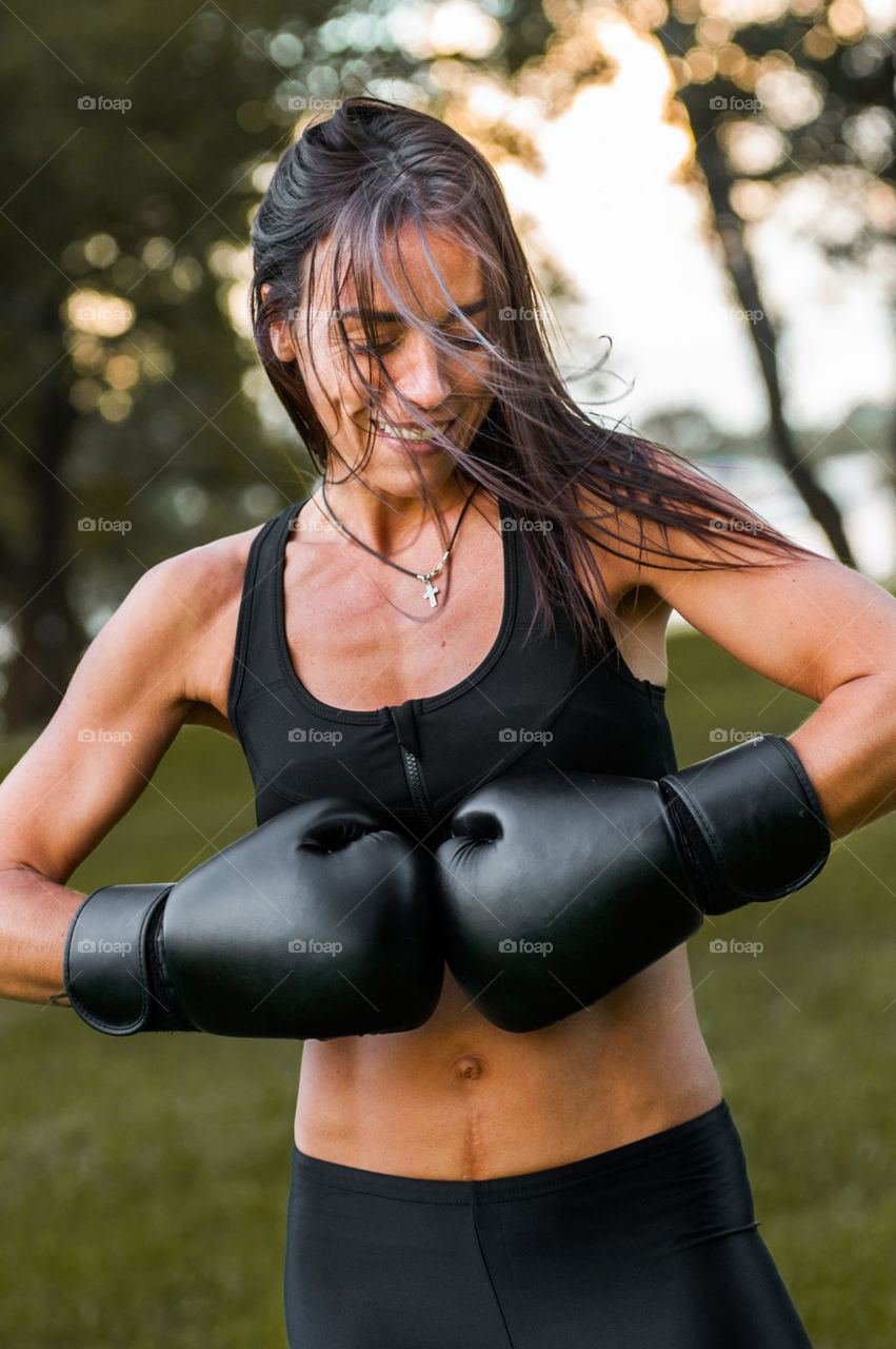 beautiful girl of athletic build, in a sulfur tracksuit and black boxing gloves, warming up in nature, outdoors