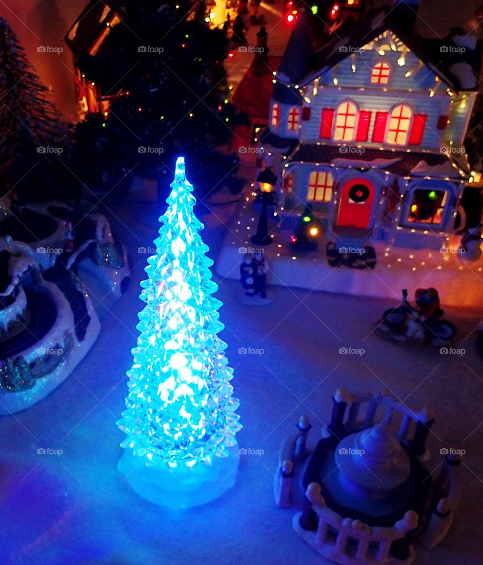 A bright blue tree in a Christmas village display. 