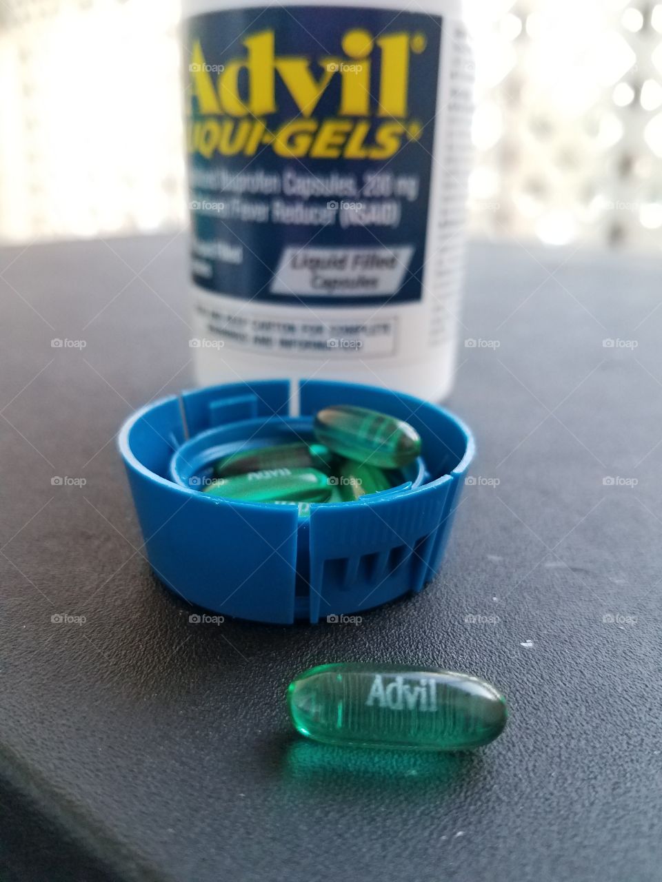 Advil liquigels in cap with Advil bottle in the background