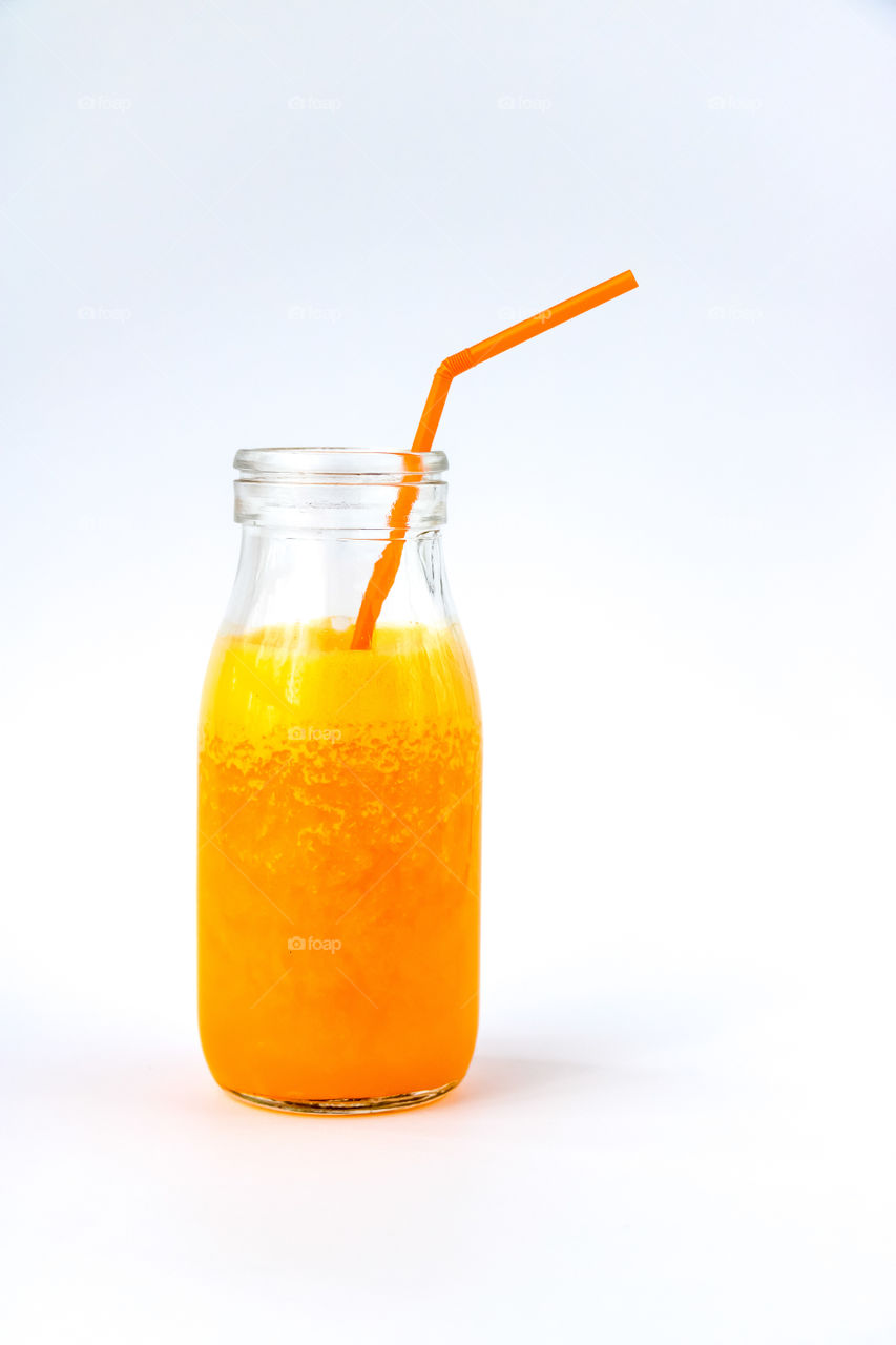 Orange juice in a glass bottle on a white background.