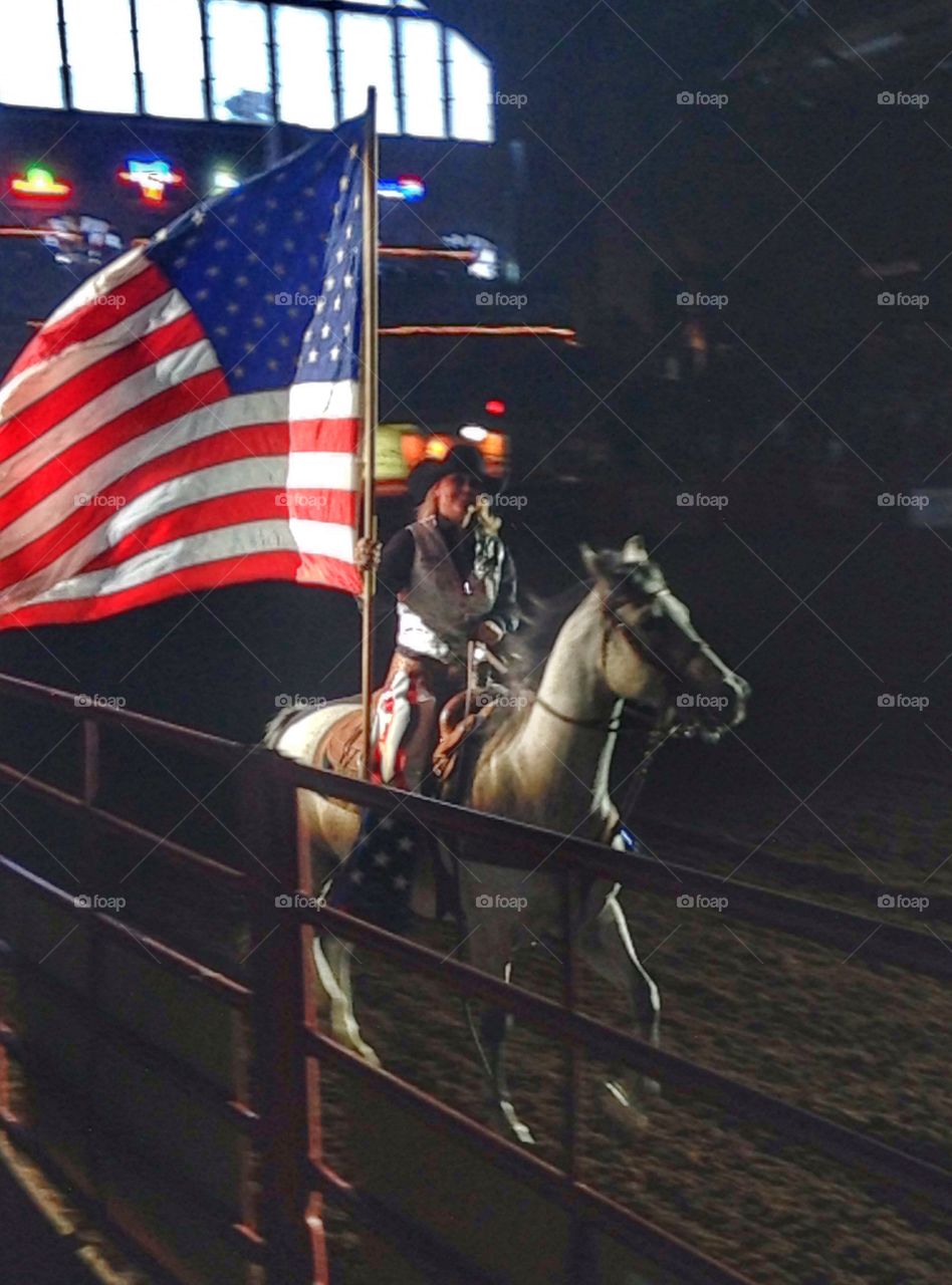 Stand up for pride. Woman holding American flag while riding a horse