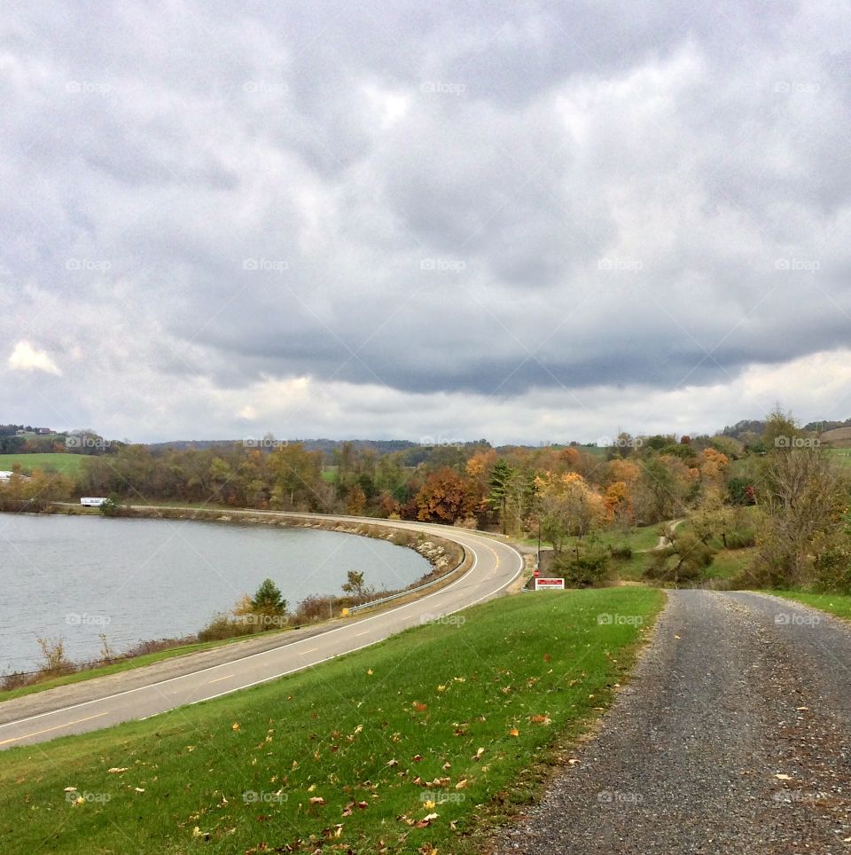 Roads beside a lake, cloudy sky and autumn leaves