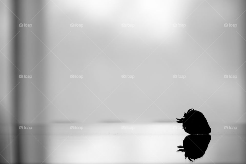 A silhouet of a strawberry and its reflection