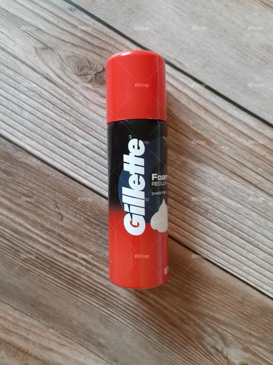 A  close up photo of a man's product Gillette Foamy Regular Shave Cream on a wood background.