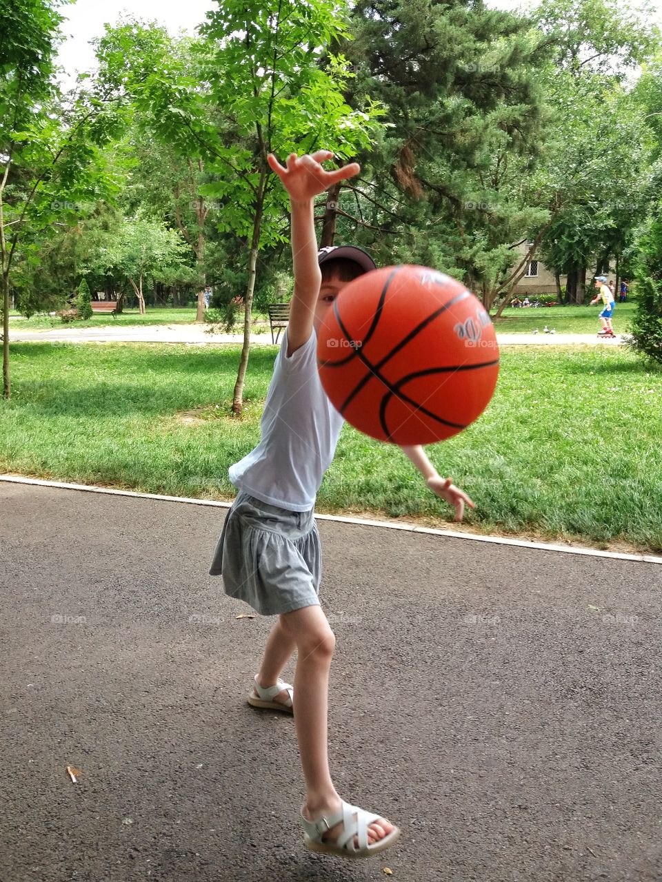 Girl playing basketball with an orange ball in summer