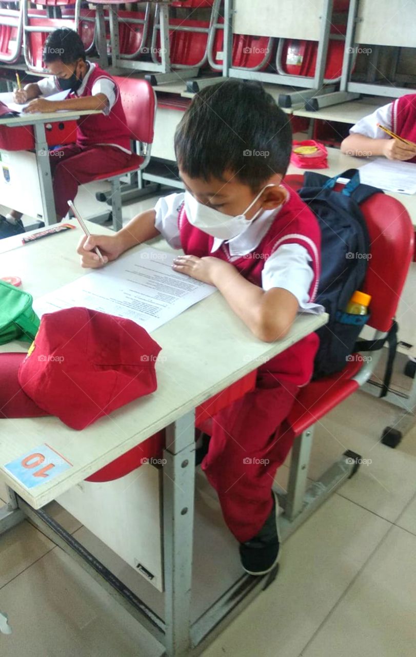 A boy doing examination at his class during covid 19 pandemic. He only goes to school twice a week.
