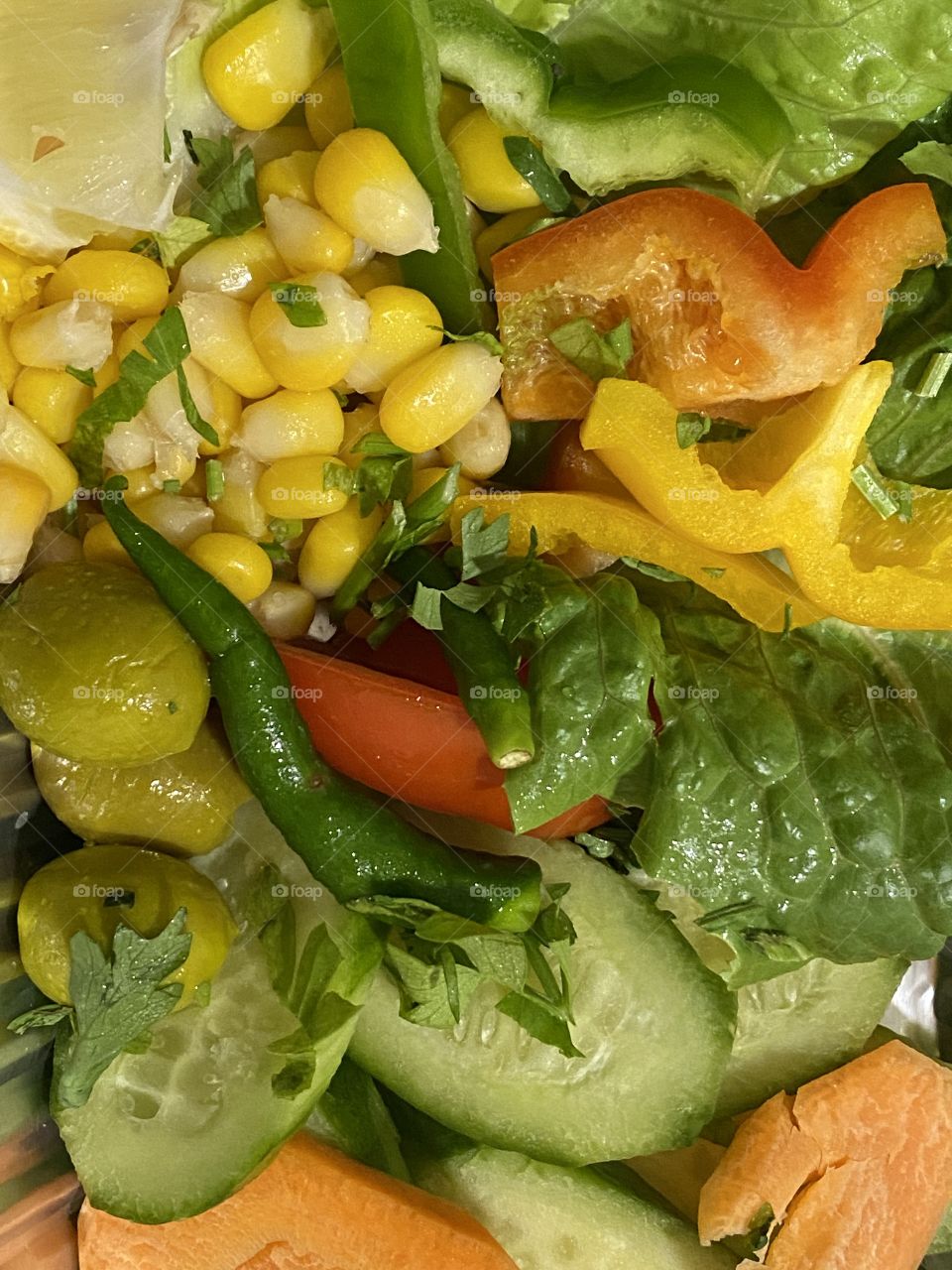 Vegetable salad close up photo, photography of vegetable salad includes capsicum yellow, capsicum green, tomatoes, green olive, cucumber,corn,chilies, carrot,leaves etc