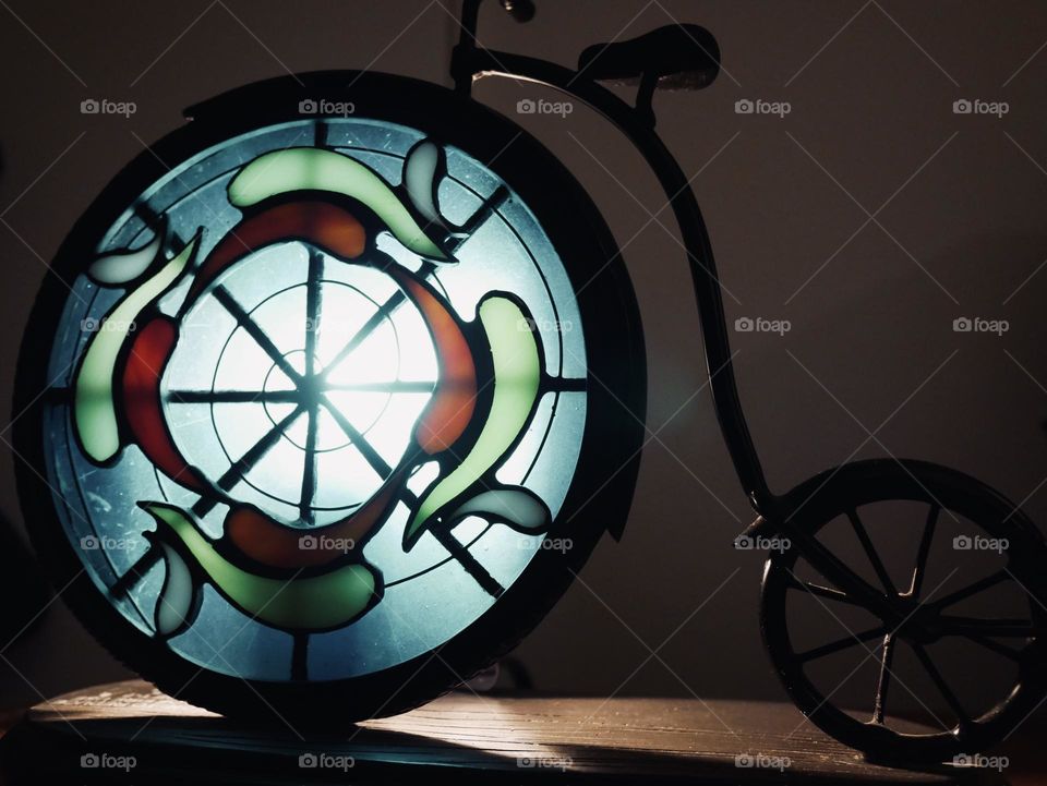 Stained glass bicycle lamp. Cool, dramatic tones, and shadows. 