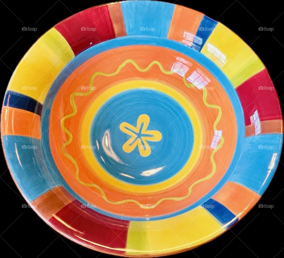 A vibrant serving bowl bursts with color—bold orange, yellow, red, light blue, and deep navy in a striking, contrasting design that catches the eye and adds energy to any table.