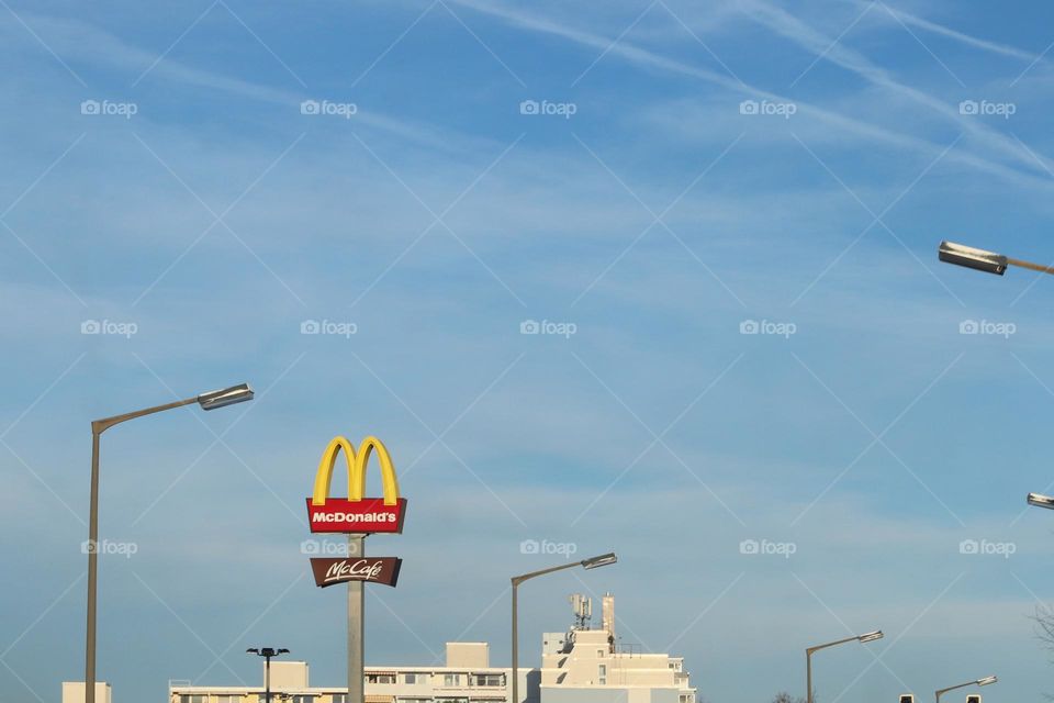 McDonald's sign next to street lamp on blue sky in city 