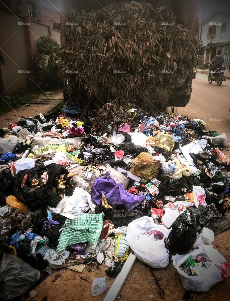 spoilt refused bin truck on the road side, with some of the trashes on the street.