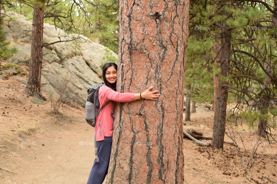 Woman hugging a big tree in forest