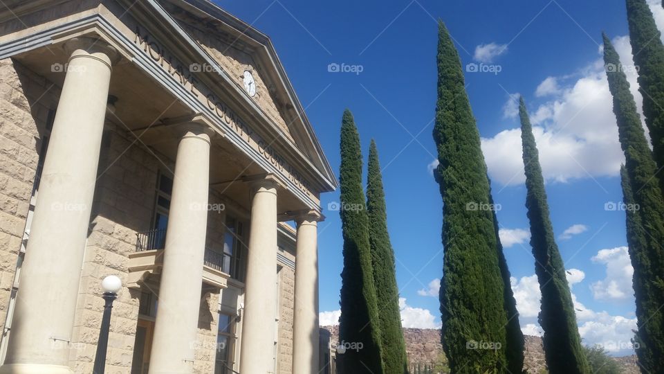 a courthouse with cypress trees and blue sky