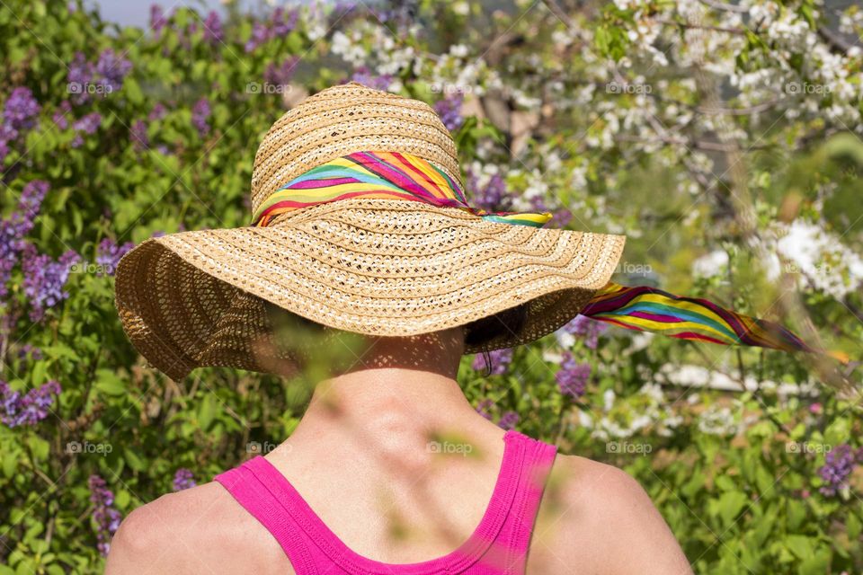 A woman with hat from behind in the garden