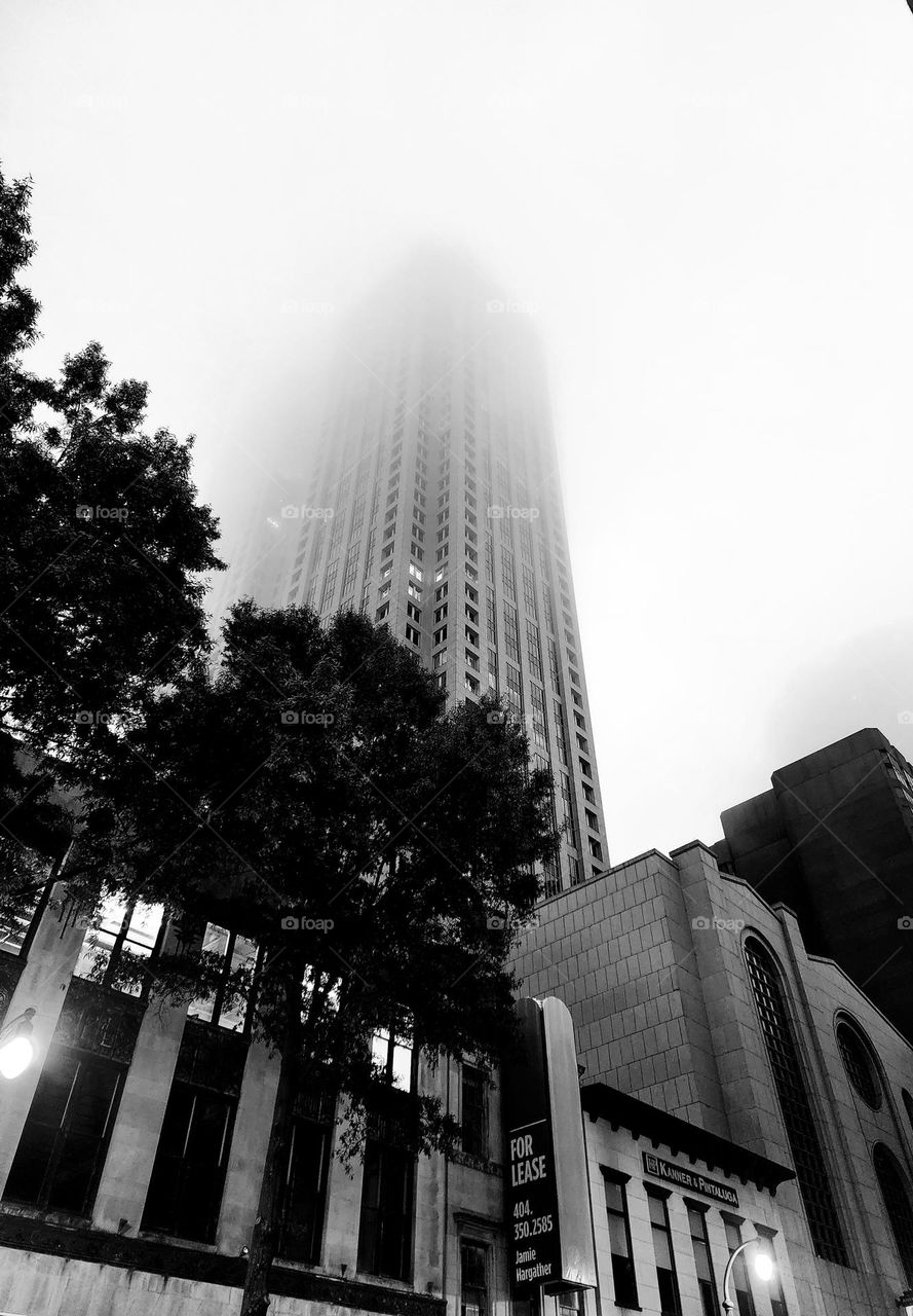 A skyscraper disappears into heavy morning mist on a warm and humid summer morning