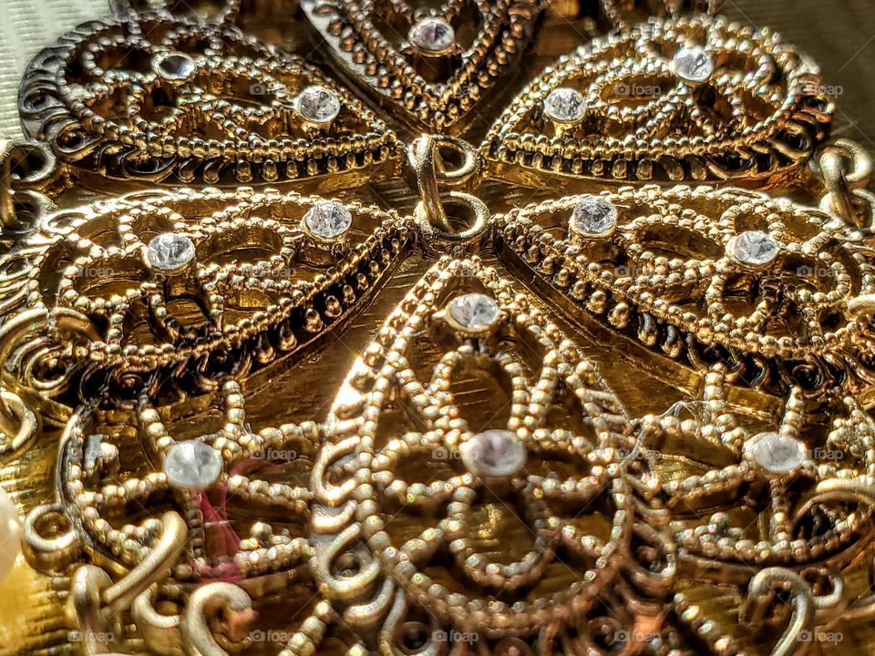 Close up shot  of earring with patterns, design,  stones and gold color.