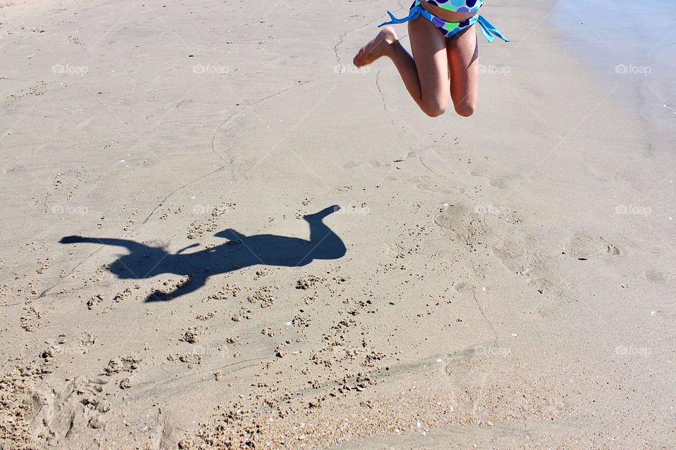 Women's shadow reflecting on the sand beach