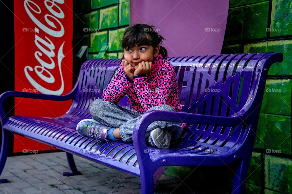 Cute girl on a purple bench