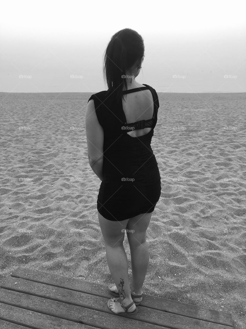 A girl on the beach is enjoying the view. Black and white. The picture is taken on a beautiful evening in Spain. 