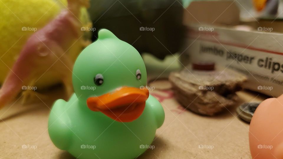 Green rubber duck in front of knick knacks