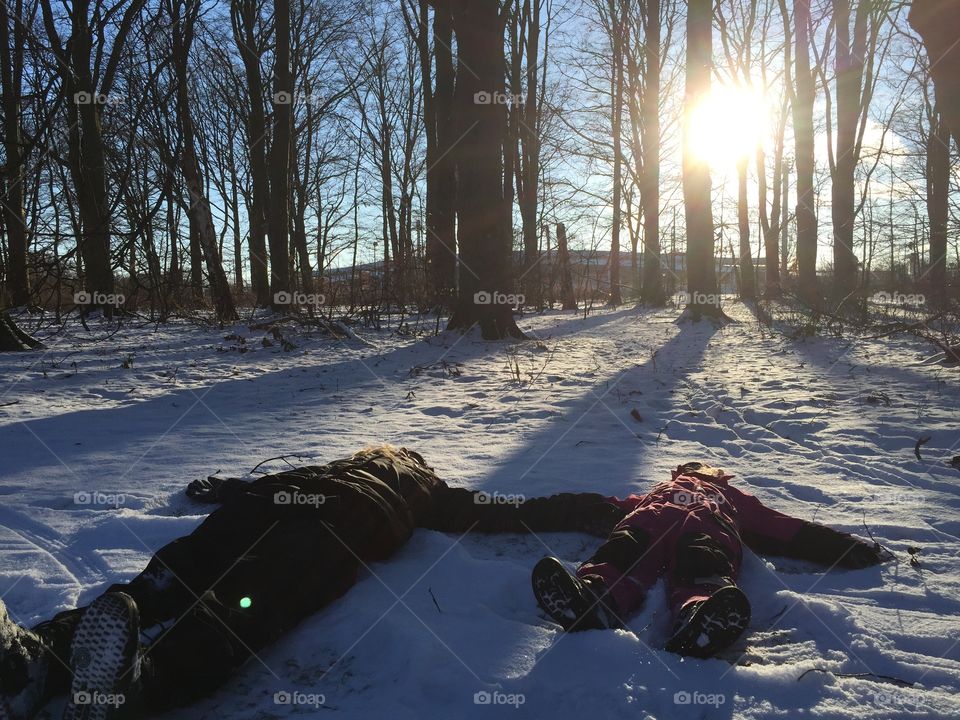 Mother and doughter making snow angels in the snow in Sweden.