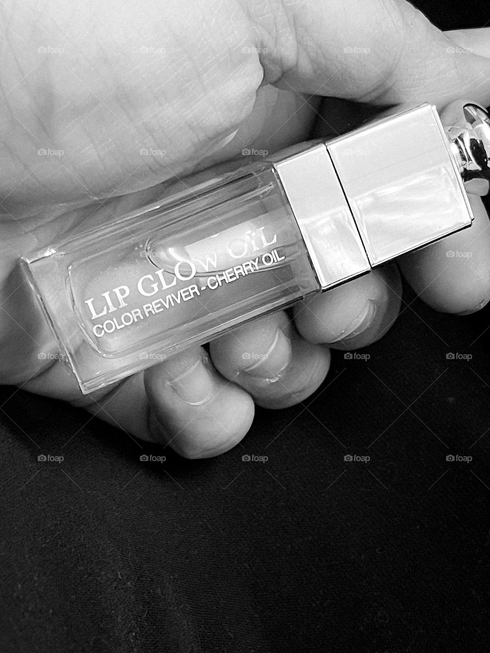 A human hand holding a lipgloss in black and white mode 