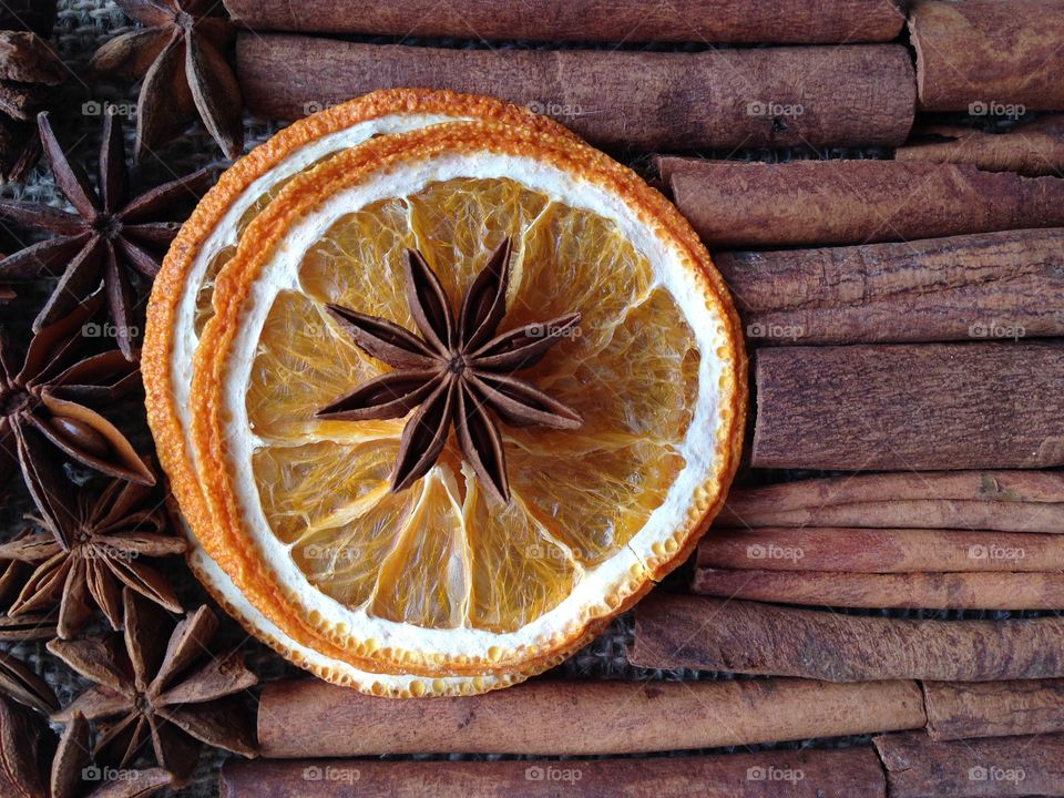 Dry slices of orange with anise stars on the background of cinnamon sticks. Food background. Space for text.