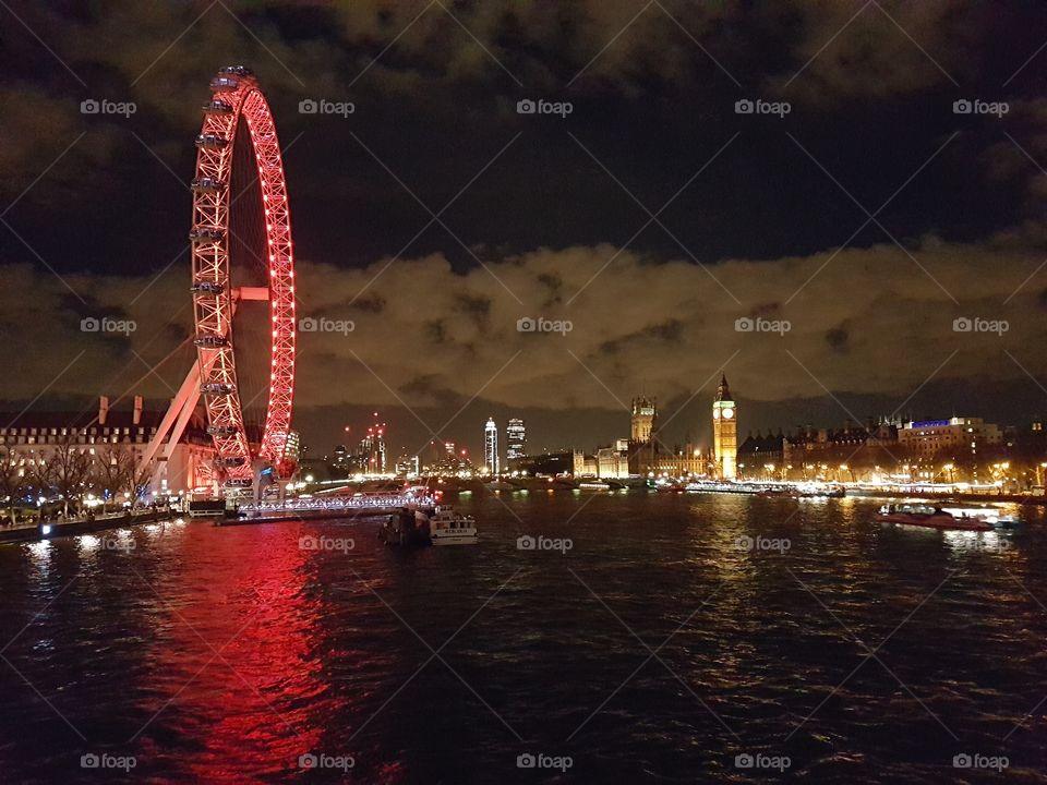 Skyline of London, UK from a bridge crossing the Thames river during the night
