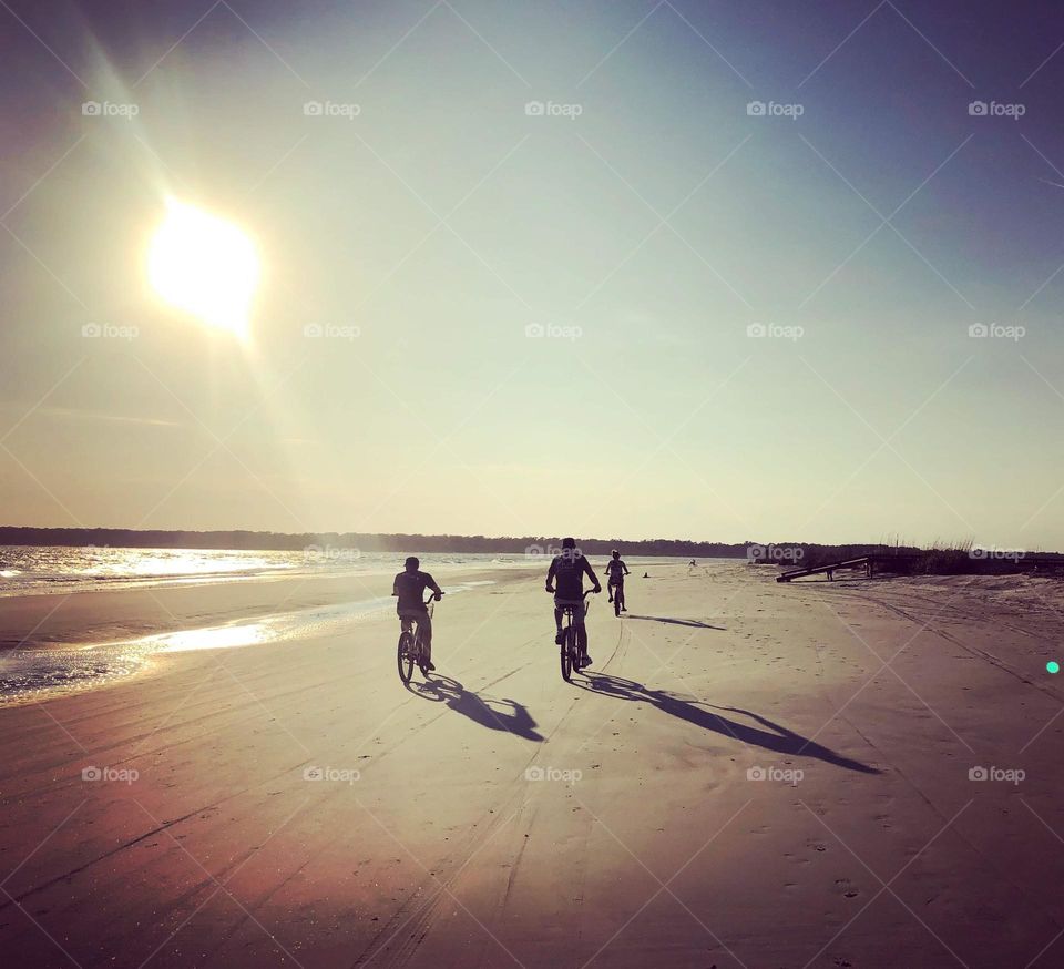 Family bike ride as the sun sets over a beach on the southern coast of the United States 