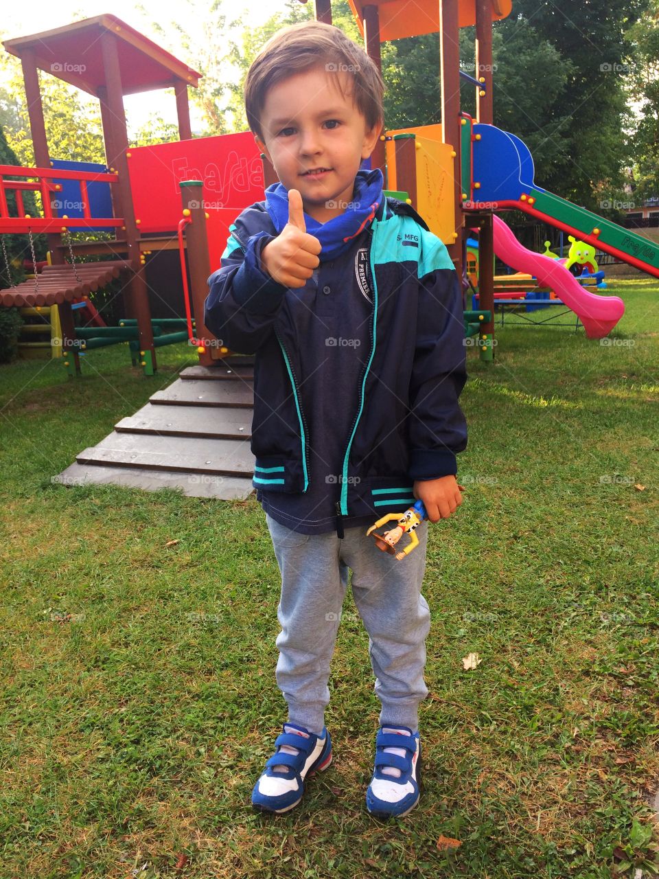 Boy showing thumbs up gesture in playground