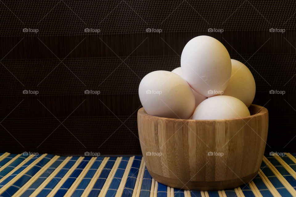 white eggs in a bowl with dark background in a striped table homemade  morning natural light