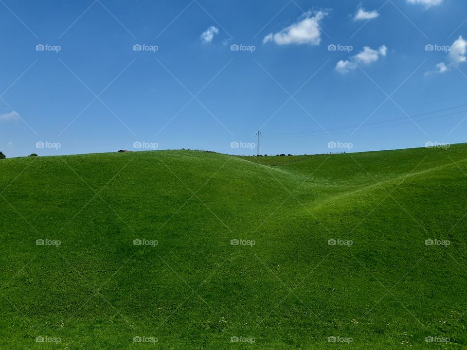 green fields at the mountains under a blue sky