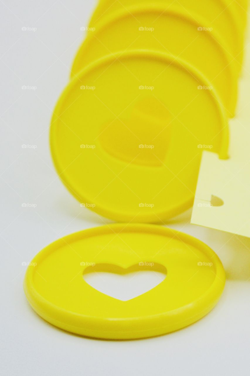 Yellow discbound  discs with heart-shaped cut-out in discbound-punched yellow paper on white background 