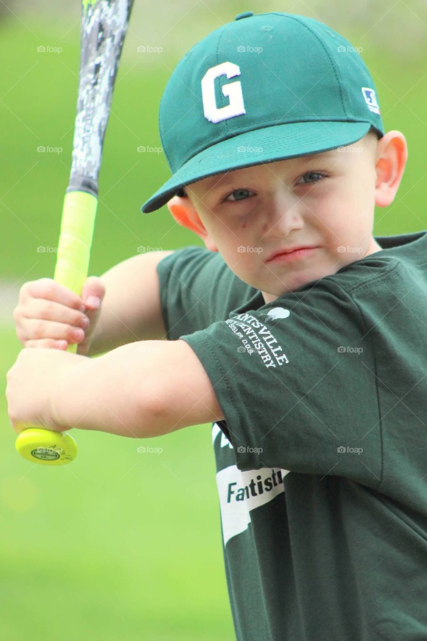 A serious look of determination and focus as he is posing for the camera in his best batting stance. 