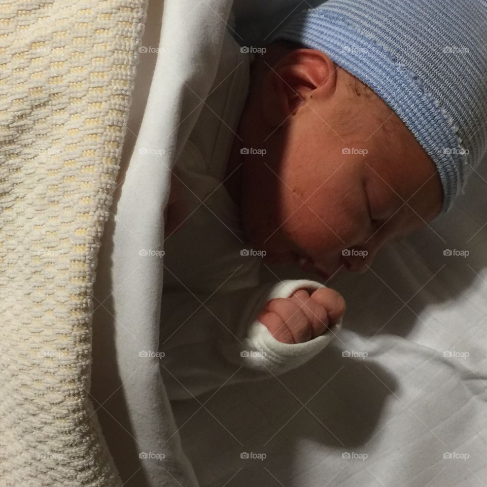 Baby boy in cap sleeping on bed