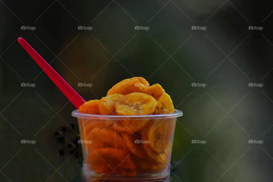 A cup of yellow snaks with spoon