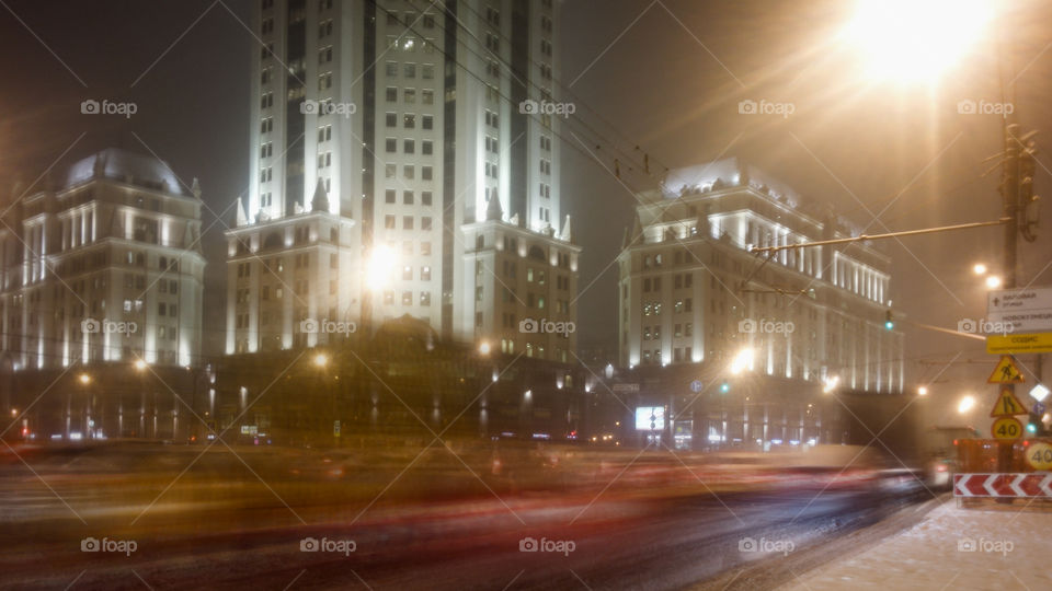 Night street with blurred silhouettes of the cars passing by