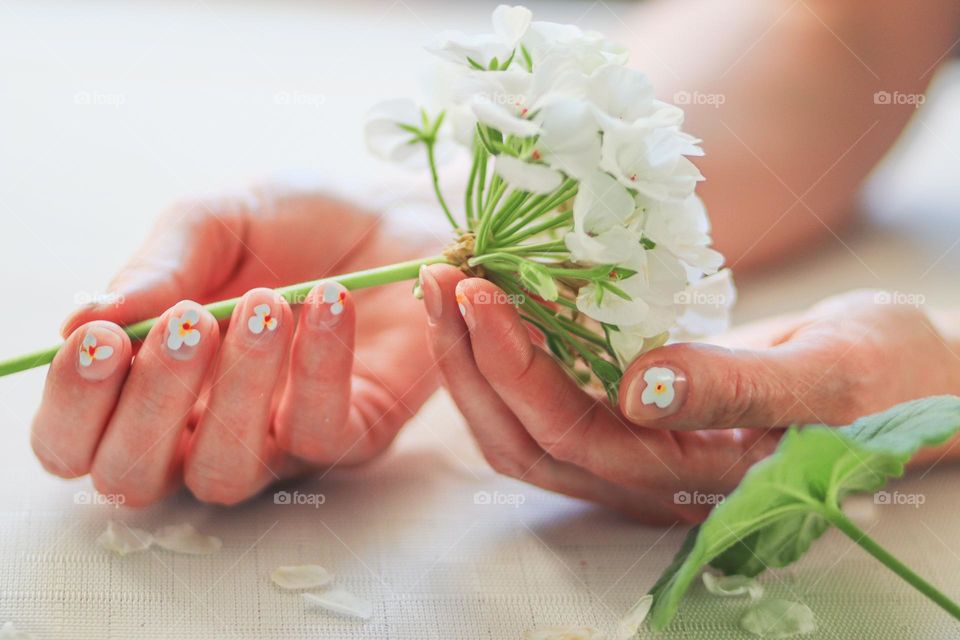 Hands with manicure in natural colors and flower