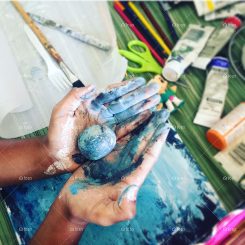 Child making art with hands using paint and clay